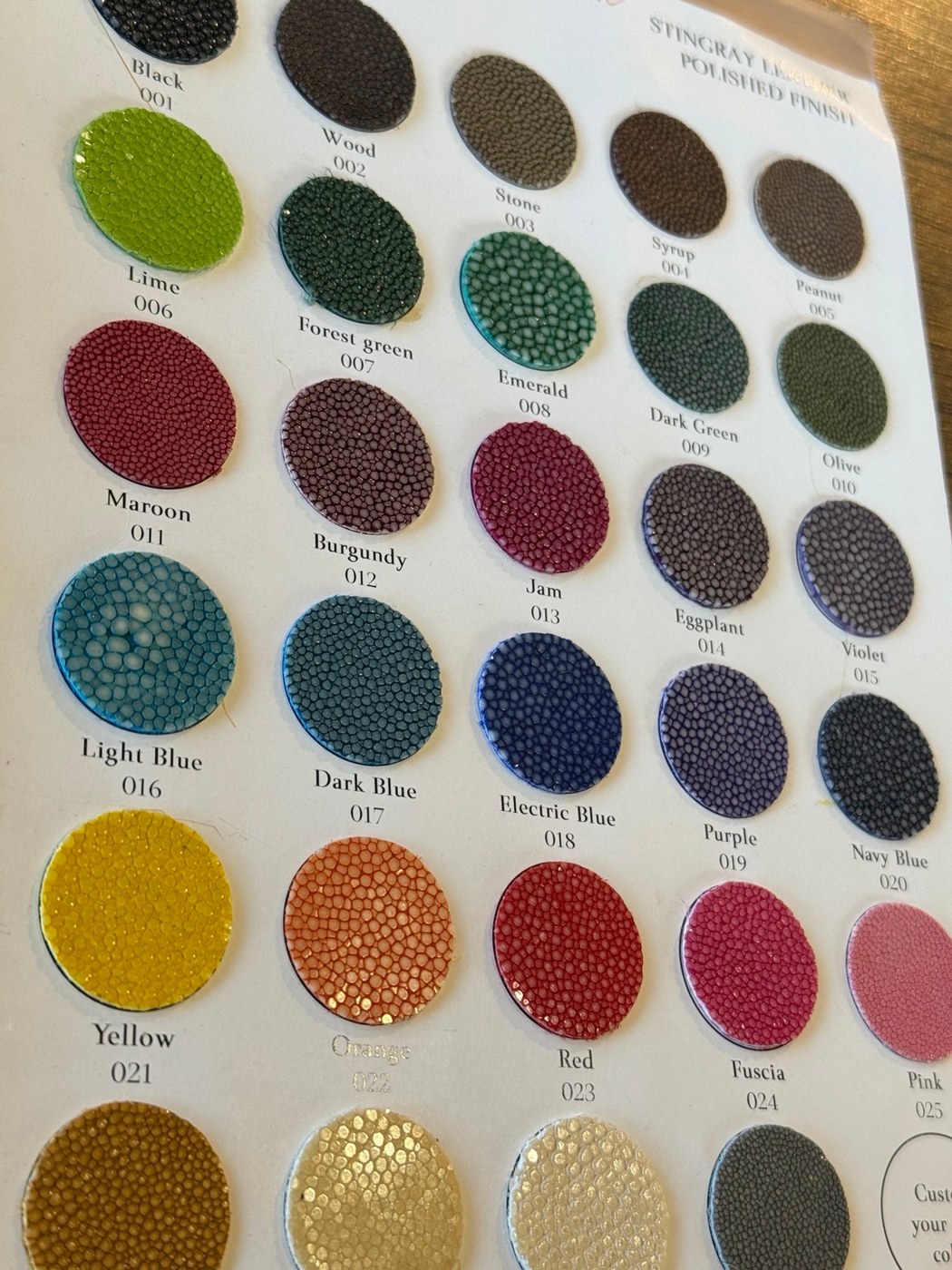 エイ革の丸いカラーサンプルが色名とともに並ぶ見本帳